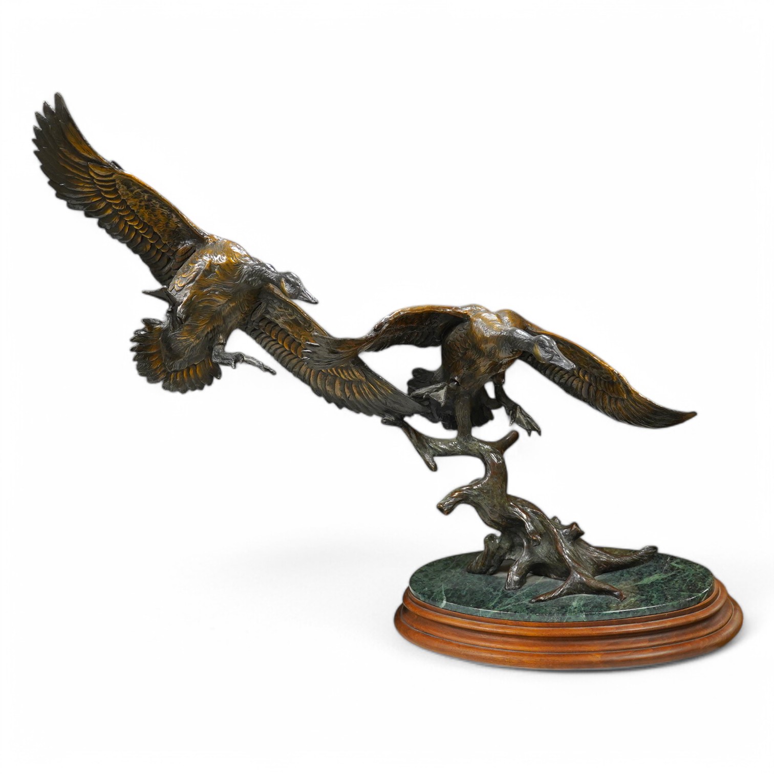 A modern large cast bronze sculpture of two flying geese, on an oval plinth, 90cm wide. Condition - good